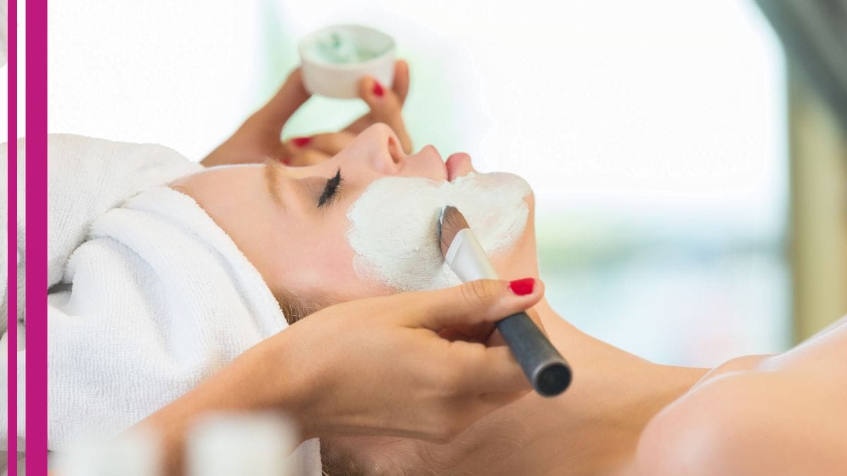 An esthetician applies a face mask for her client.
