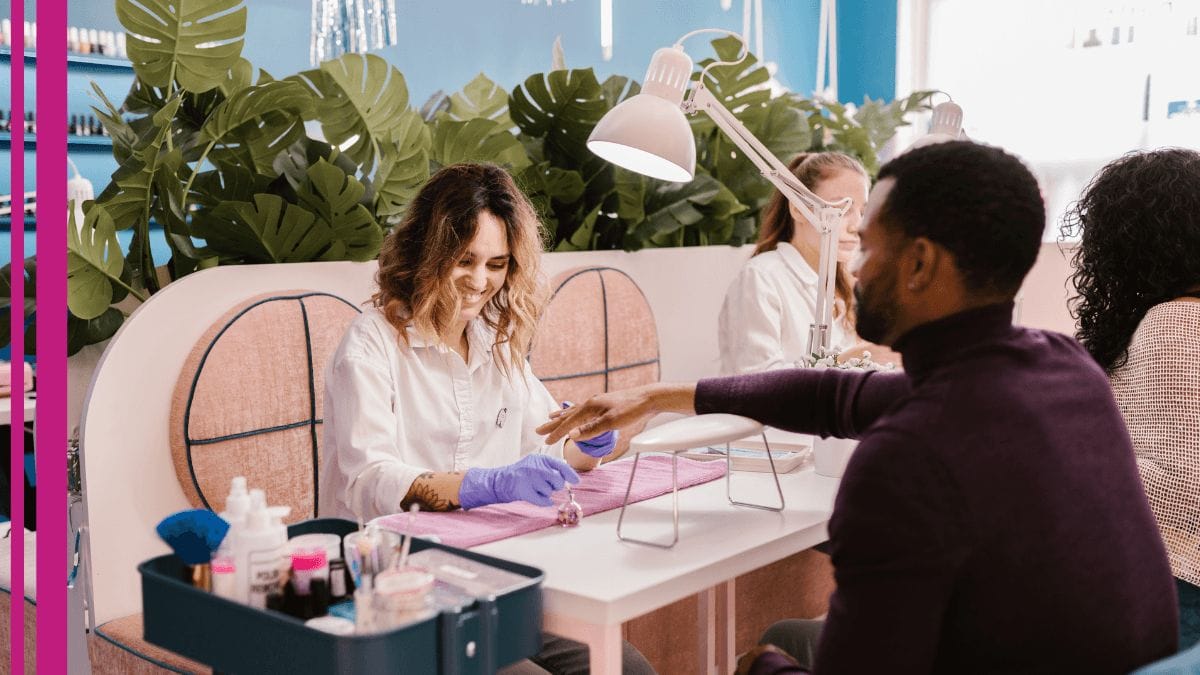 A nail tech tries a new technique on her client after reading nail tech business tips.