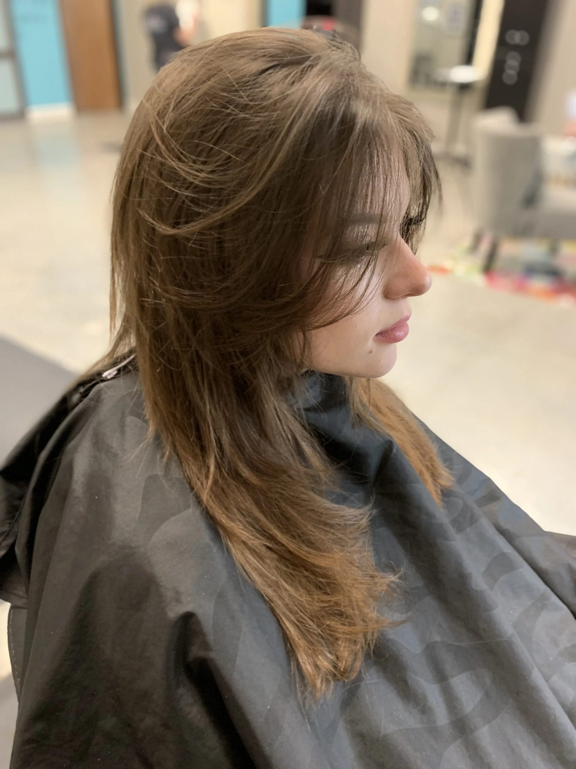 Side profile of a woman with layered brown hair, styled in soft waves, celebrating beauty and empowerment during Black History Month.