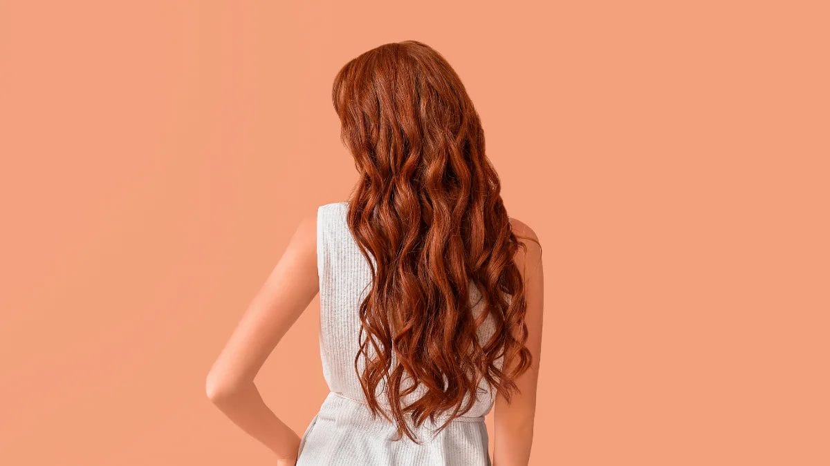 A client shows off her pumpkin spice hair color, a fall beauty trend.