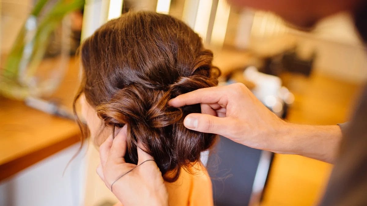 A stylist creates an updo bun for her thanksgiving beauty look.