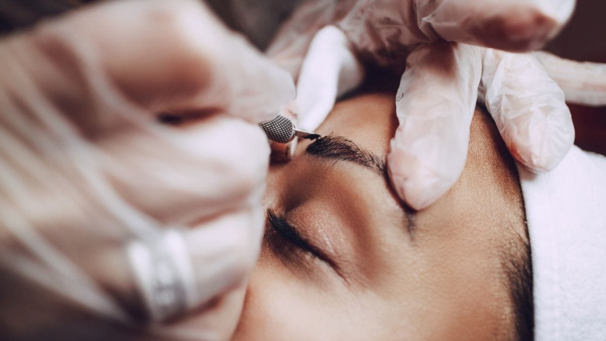 An eyebrow specialist uses her eyebrow education to tweeze a client's brows.