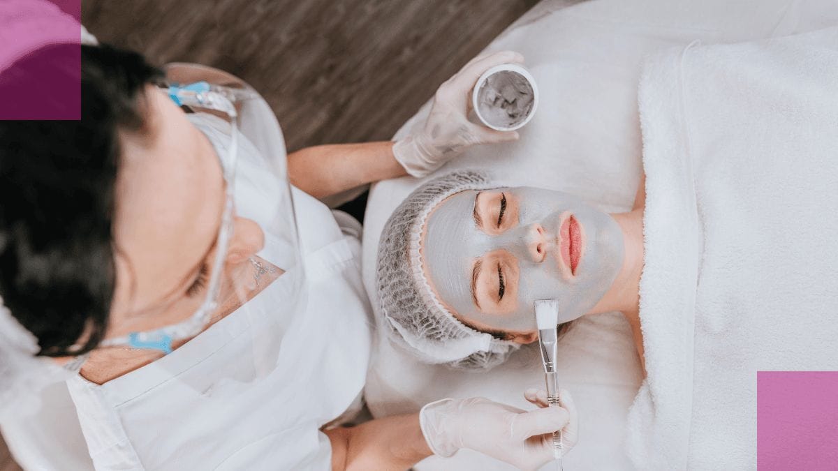 An esthetician applies a mask to her clients face  while thinking about esthetician salary and what she could make.