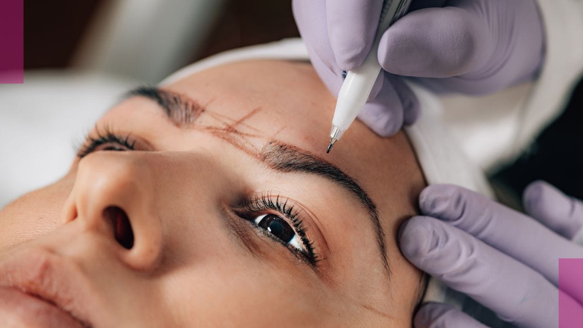 A brow technician with liability insurance maps out her client's eyebrows with her pencil.