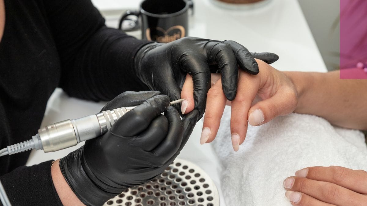 A nail tech explains how to get rid of green nail syndrome to her client while fixing her nails.