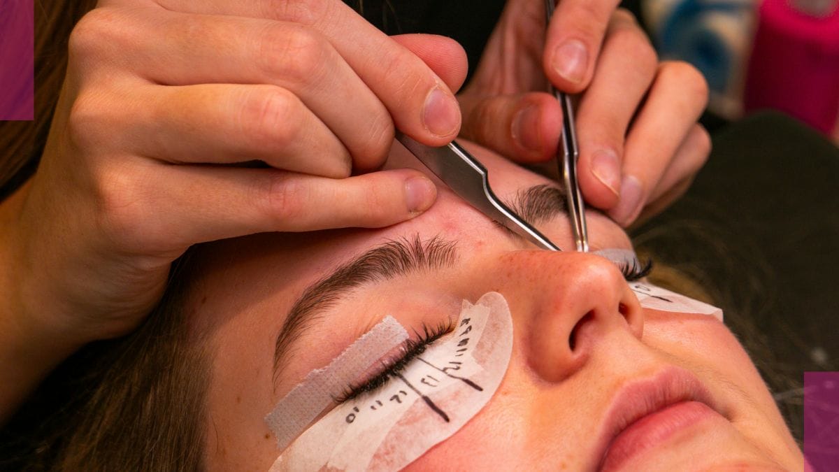 A beauty pro uses tweezers to apply eyelash extensions.