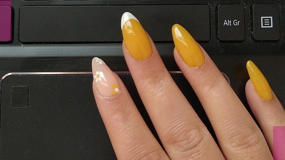 A client shows off her dainty flower design on orange spring break nails.