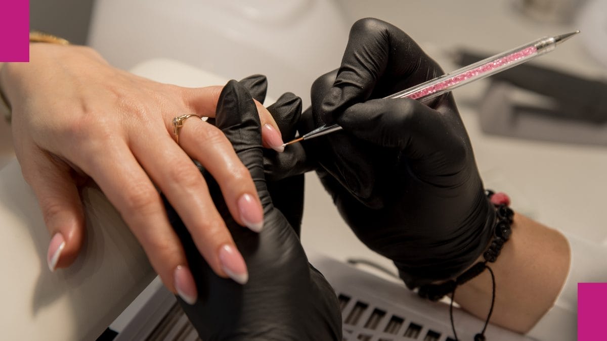 Nail technician carefully applies design to client's nails